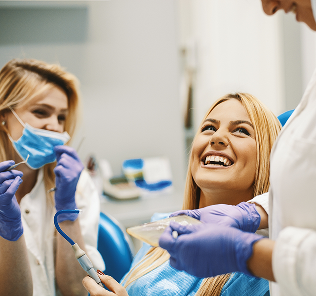 Woman in dental treatment chair smiling up at her orthodontist in Gilbert