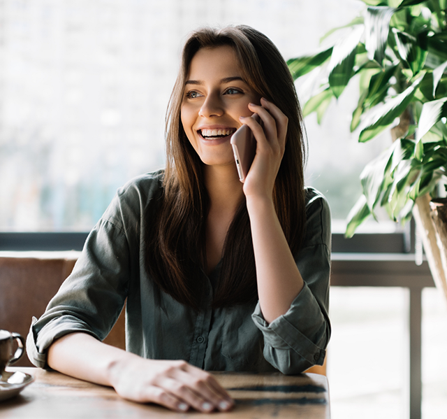 Woman smiling while talking on phone with orthodontist about dentofacial orthopedics