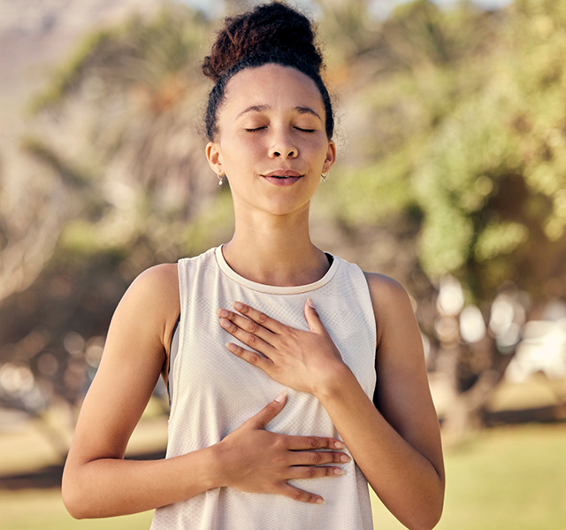 Young woman standing in exercise clothes and focusing on her breathing