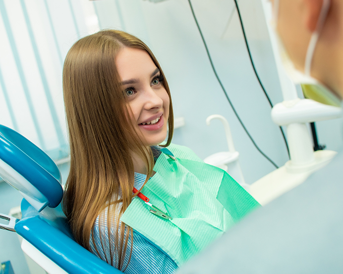 Young woman in treatment chair listening to her orthodontist