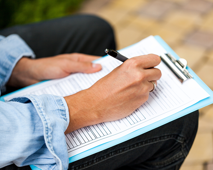 Person filling out paperwork on a clipboard