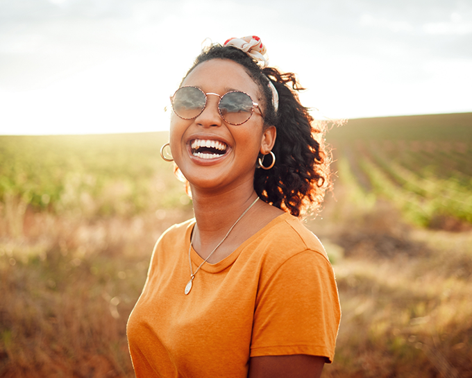 Woman with sunglasses and ponytail smiling outdoors