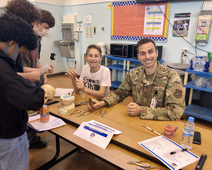 Doctor Larson in his Air Force uniform sitting at a table with kids and models of teeth