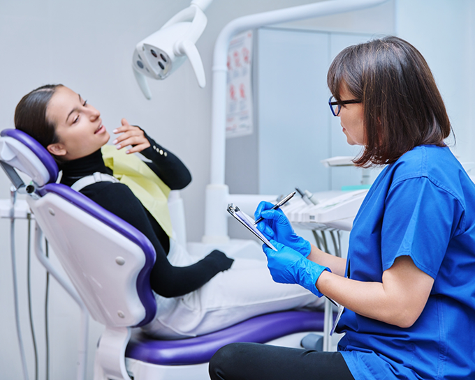 Woman in dental treatment chair explaining her orthodontic emergency to a team member