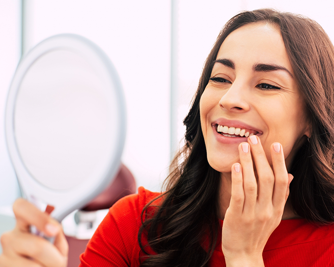 Woman looking at her smile in a mirror