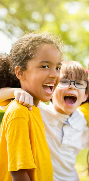 Two kids laughing together outdoors