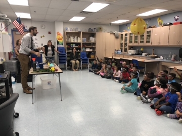 Classroom of children sitting on floor watching presentation