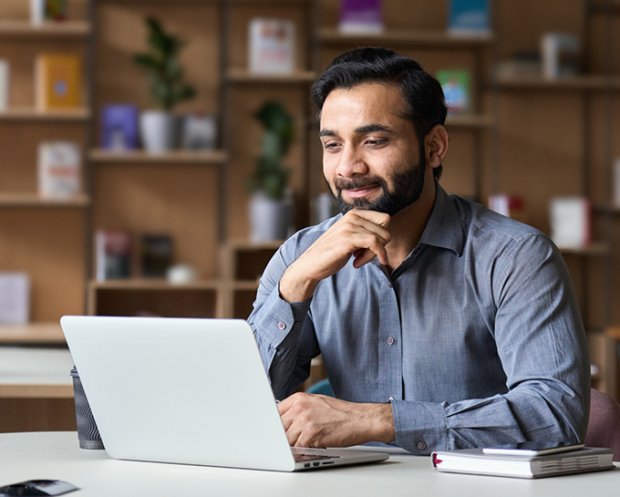 Smiling man sitting at table and using his laptop